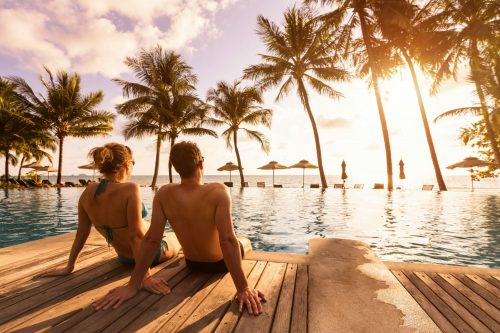 Langzeiturlaub 2022, Langzeiturlaub 2023, Überwintern im Warmen, Reisebüro Paar am Strand mit Palmen: Symbolbild für Langzeiturlaub 2022, Langzeiturlaub 2023