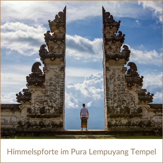 Bali Sehenswürdigkeiten wie die Himmelspforte im Pura Lempuyang Tempel; im Bild ein altes Bauwerk, das aus zwei spitz zulaufenden und verzierten Mauern besteht; in der Mitte dadurch ein nach oben geöffneter Spalt, in dem klein ein Mensch in längerem Rock steht