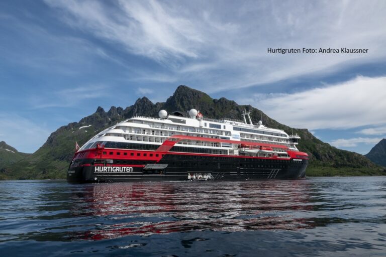 Postschiffreise mit Hurtigruten bei REISEBÜRO Wache, Erfurt: großes Schiff in schwarz, rot, weiß fährt durchs dunkle Meer, im Hintergrund grün bewachsene Felsen, der Himmel mit weißen Wölkchen