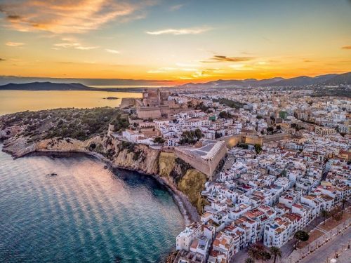 Ibiza Urlaub buchen bei REISEBÜRO Wache Erfurt; im Bild: Blick auf Ibiza-Stadt im Sonnenuntergang von oben; Häuser bis zur Küste, dann Meer