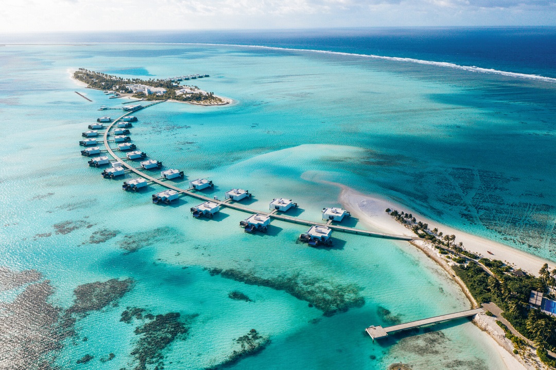 Malediven Hotel von REISEBÜRO Wache: im Bild: Overwater-Bungalows an einem Steg von Insel zu Insel, Blick von oben aufs türkisfarbene Meer und die Bungalows