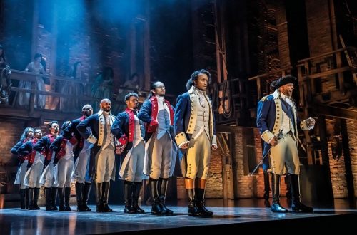 Das Musical Hamilton in Hamburg: Szenenbild mit zwei Reihen Soldaten, an der Spitze der ersten Reihe links: Alexander Hamilton