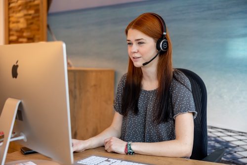 REISEBÜRO Wache - TEC Erfurt erreichbar über Telefon, WhatsApp, E-Mail; Symbolbild: Mitarbeiterin mit Headset vor dem Computer telefoniert mit einem Kunden