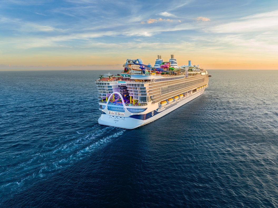 Icon Of The Seas Buchen Bucket List Reisebuero Erfurt Eine Kreuzfahrt auf der Icon of the Seas buchen, ein Bucket-List-Traum, bestens beraten erfüllbar im REISEBÜRO Wache, Erfurt; im Bild: Die Icon of the Seas fährt vom Betrachter weg auf dem Meer dem Sonnenuntergang entgegen; man sieht das Heck und die vielen Decks einschließlich Rutschen- und Pooldeck oben