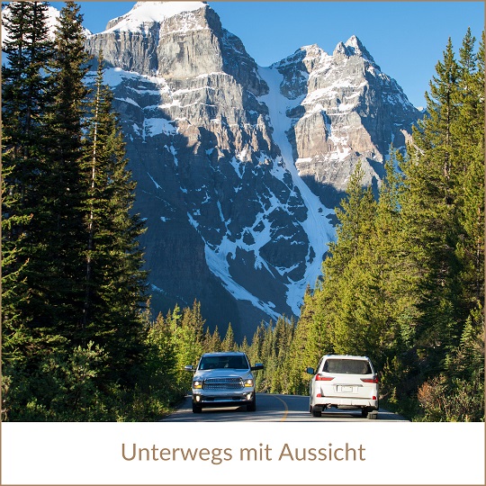 Kanada Rundreise Urlaub 2024 buchen in Erfurt bei REISEBÜRO Wache; im Bild: Zwei Autos auf einer Straße zwischen hohen Nadelbäumen, im Hintergrund schneebedeckte Berggipfel