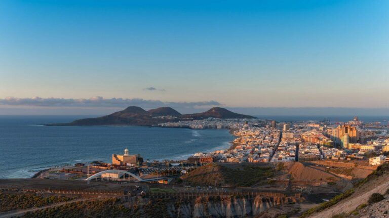 Kanaren buchen mit Gran Canaria bei REISEBÜRO Wache Erfurt; im Bild: Blick von fern auf die Stadt Las Palmas, im Hintergrund Meer und Gestein, das aus dem Wasser ragt
