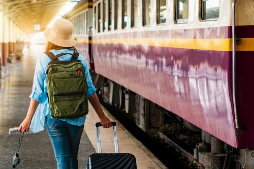 Nachhaltig reisen mit REISEBÜRO Wache, Erfurt:Frau mit Koffer und Rucksack an einem Zug