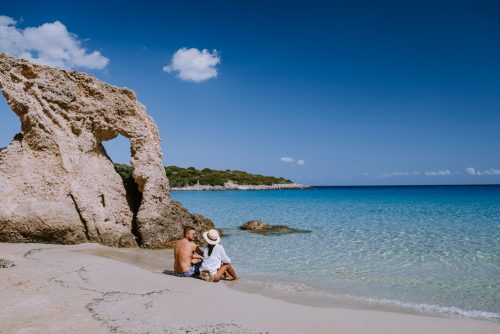 Symbolbild Griechenland 2023, REISEBÜRO Wache, Erfurt: Pärchen am Strand von Kreta, Griechenland, weißer Sand, im Hintergrund helle Steine