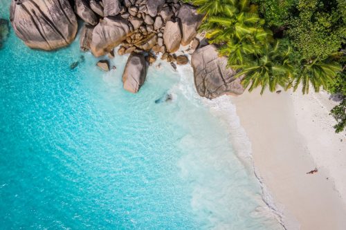 Seychellen Kreuzfahrt buchen Nicko Cruises bei REISEBÜRO Wache Erfurt, im Bild: Blick von oben auf türkisblaues Meer mit feinem Sandstrand, riesige Kiesel, grüne Bäume