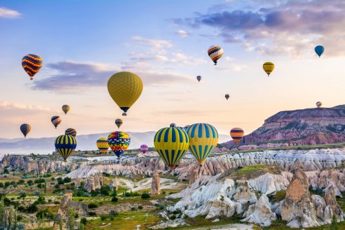 Heißluftballons steigen über hügeliger Landschaft auf: Symbolbild für Erlebnisse buchen, online buchen