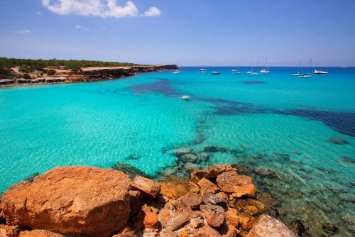 Formentera Urlaub buchen bei REISEBÜRO Wache Erfurt; im Bild: Felsen am Rande der Bucht Cala Saona, dahinter türkisfarbenes Meer