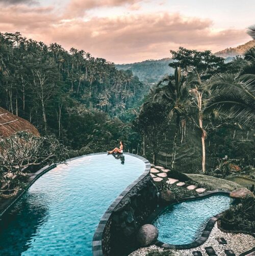 Südostasien Urlaub buchen bei REISEBÜRO Wache, Erfurt; im Bild: Frau im Infinity-Pool, umgeben von dramatisch schöner Bergszenerie und grünen Palmen