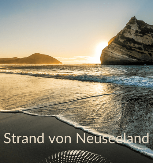Urlaub Neuseeland buchen beim REISEBÜRO Wache in Erfurt; im Bild: schwarzer Strand, kleine Wellen mit Schaumkrone, Fels im Wasser, Sonne versinkt dahinter