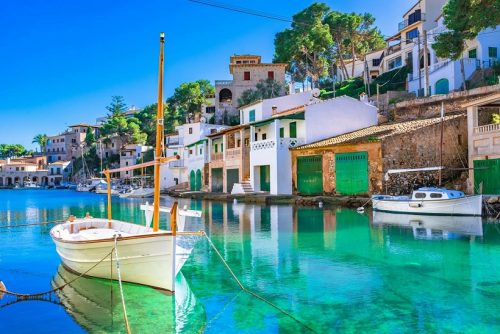 Urlaub Mallorca buchen bei REISEBÜRO Wache Erfurt; im Bild der Hafen von Cala Figuera auf Mallorca, Spanien, zu sehen ein Segelboot ohne Segel auf grünlichem Meer, daneben kleine Häuser des Küstenorts